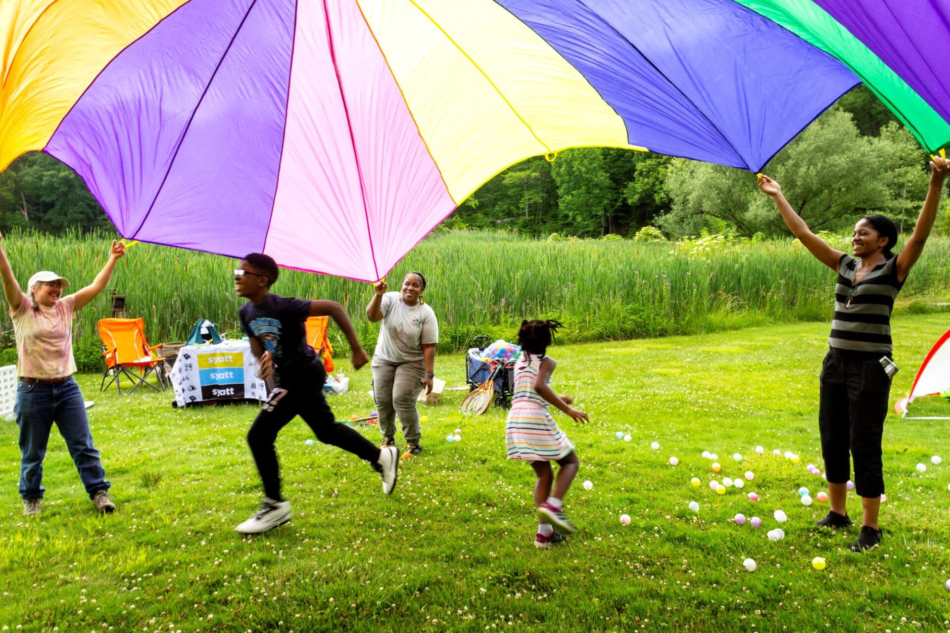 Children playing and running under a parachute during Family Fun Day.