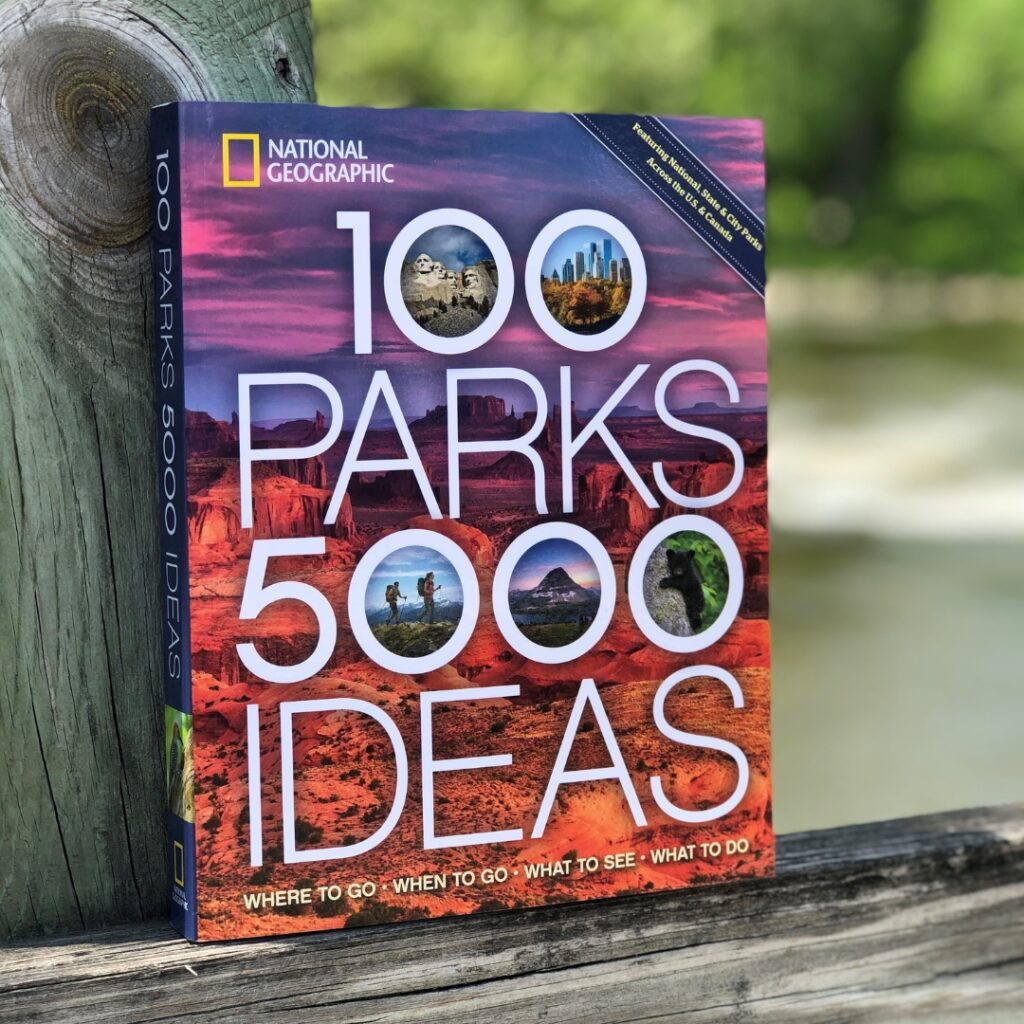 A photo of a book titled 100 Parks 5000 ideas. The cover image is a photo of a rocky Western landscape at sunset.