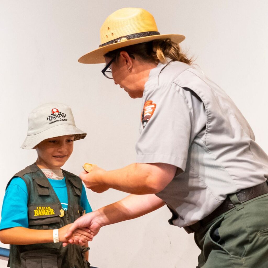 Ranger presenting child with junior ranger badge.