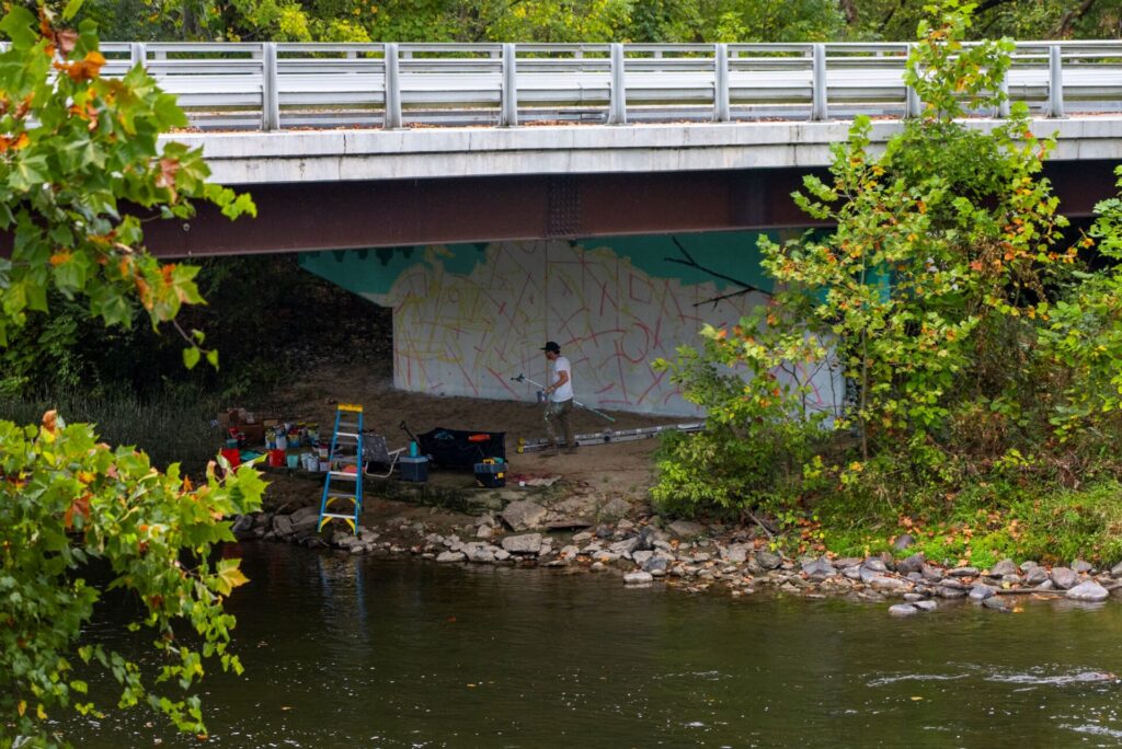 Arlin working under bridge with design outlined.