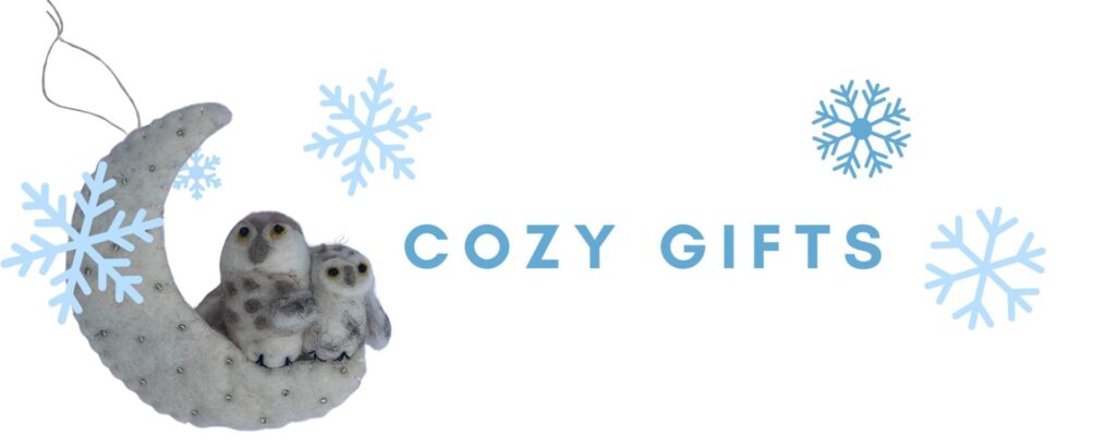 A graphic that includes a photo of a felted ornament of two owls on a crescent moon, several graphic snowflakes, and the words cozy gifts.