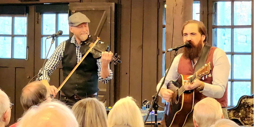 Ed Caner and David Mayfield performing for a crowd of people.