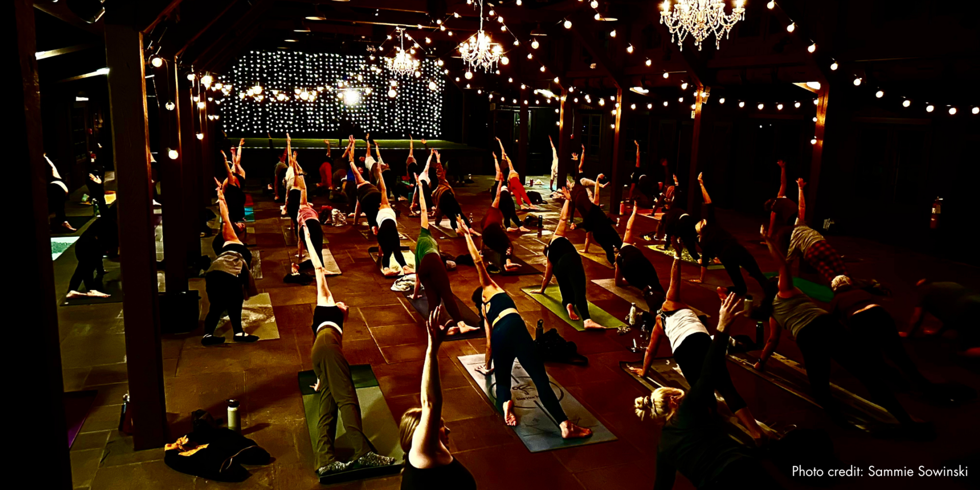 Large group of people doing a yoga pose in Happy Days Lodge.