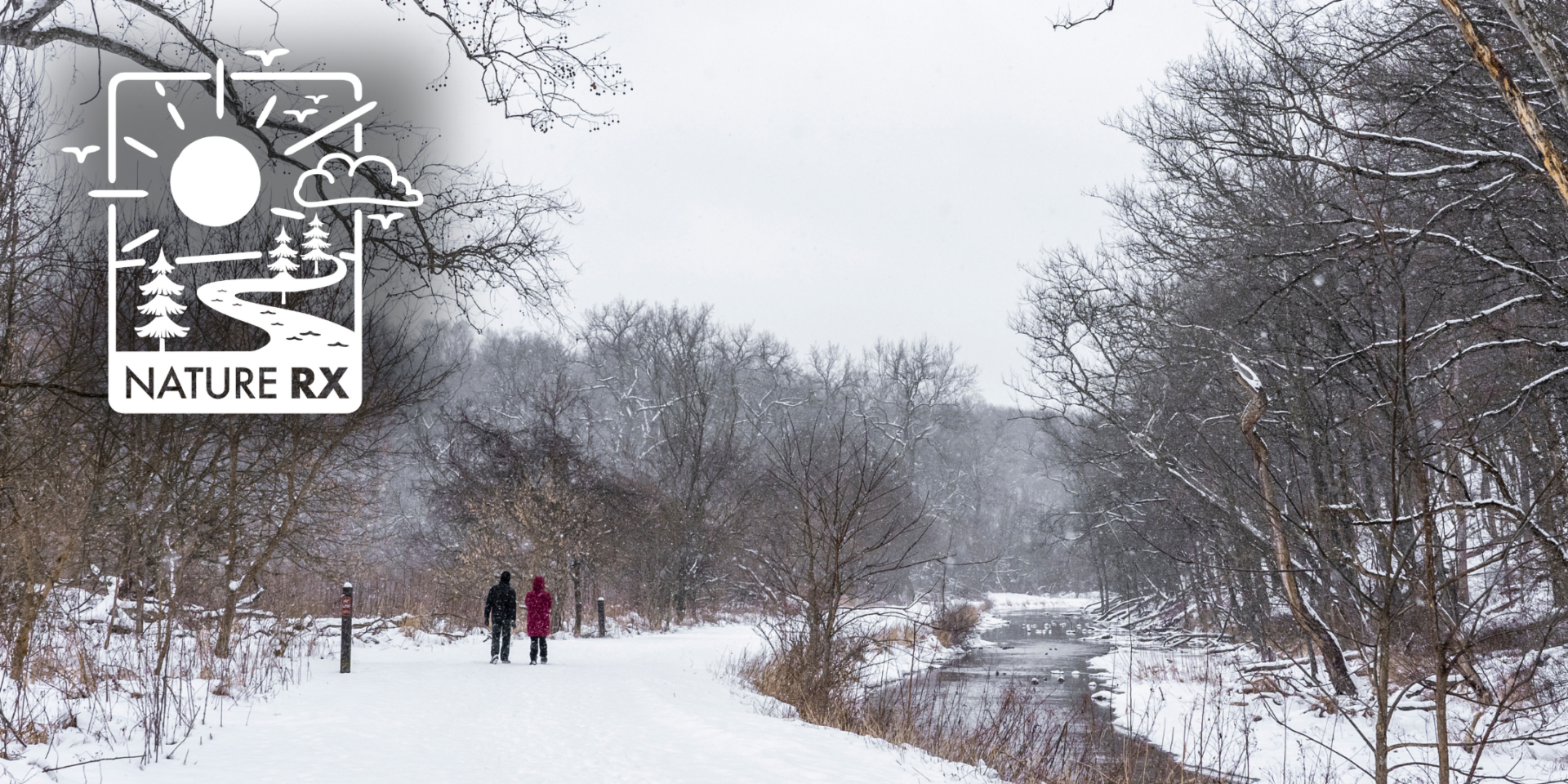 Two people walking on a snowy Towpath Trail at Station Road Bridge area.